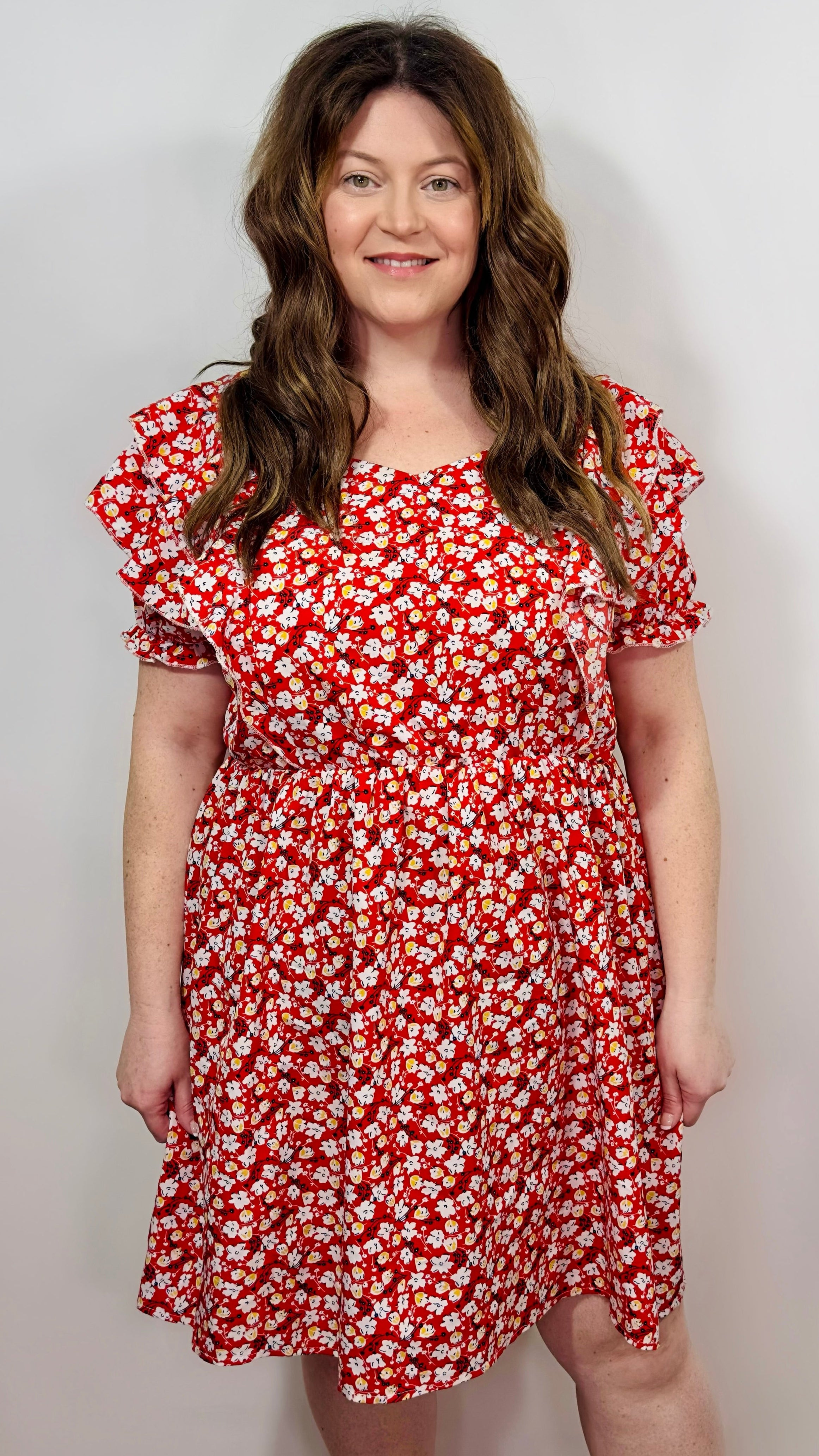 Woman wearing a red floral dress against a plain background