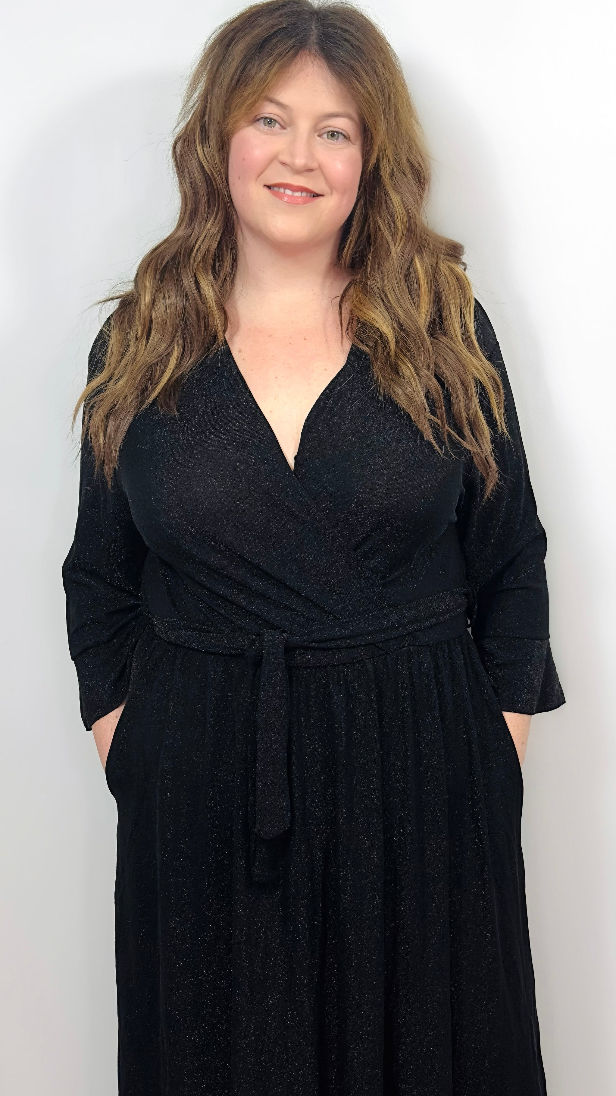 a woman wearing a black wrap dress with a white background