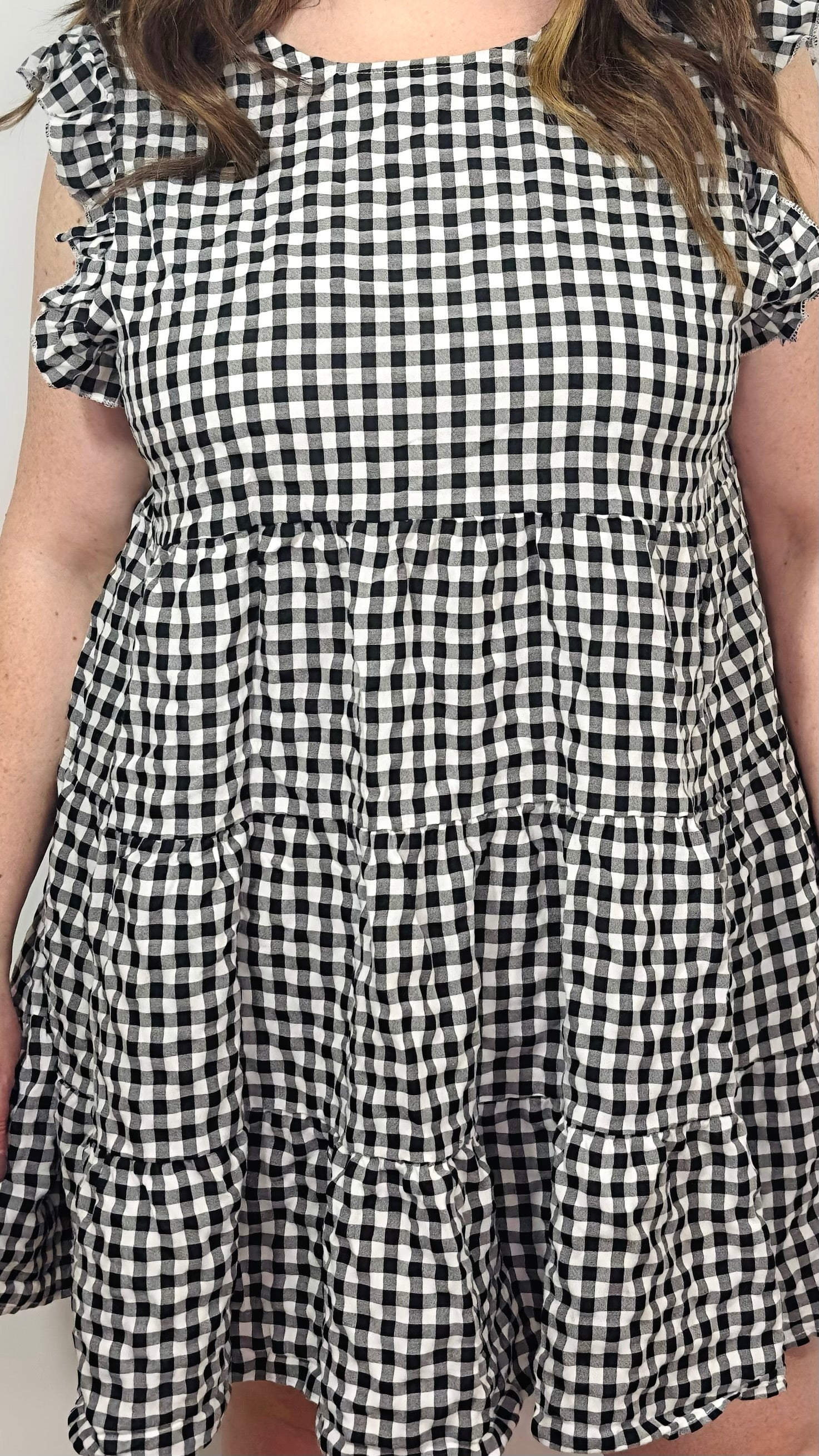 Black and white checkered dress with ruffled sleeves on a plain background