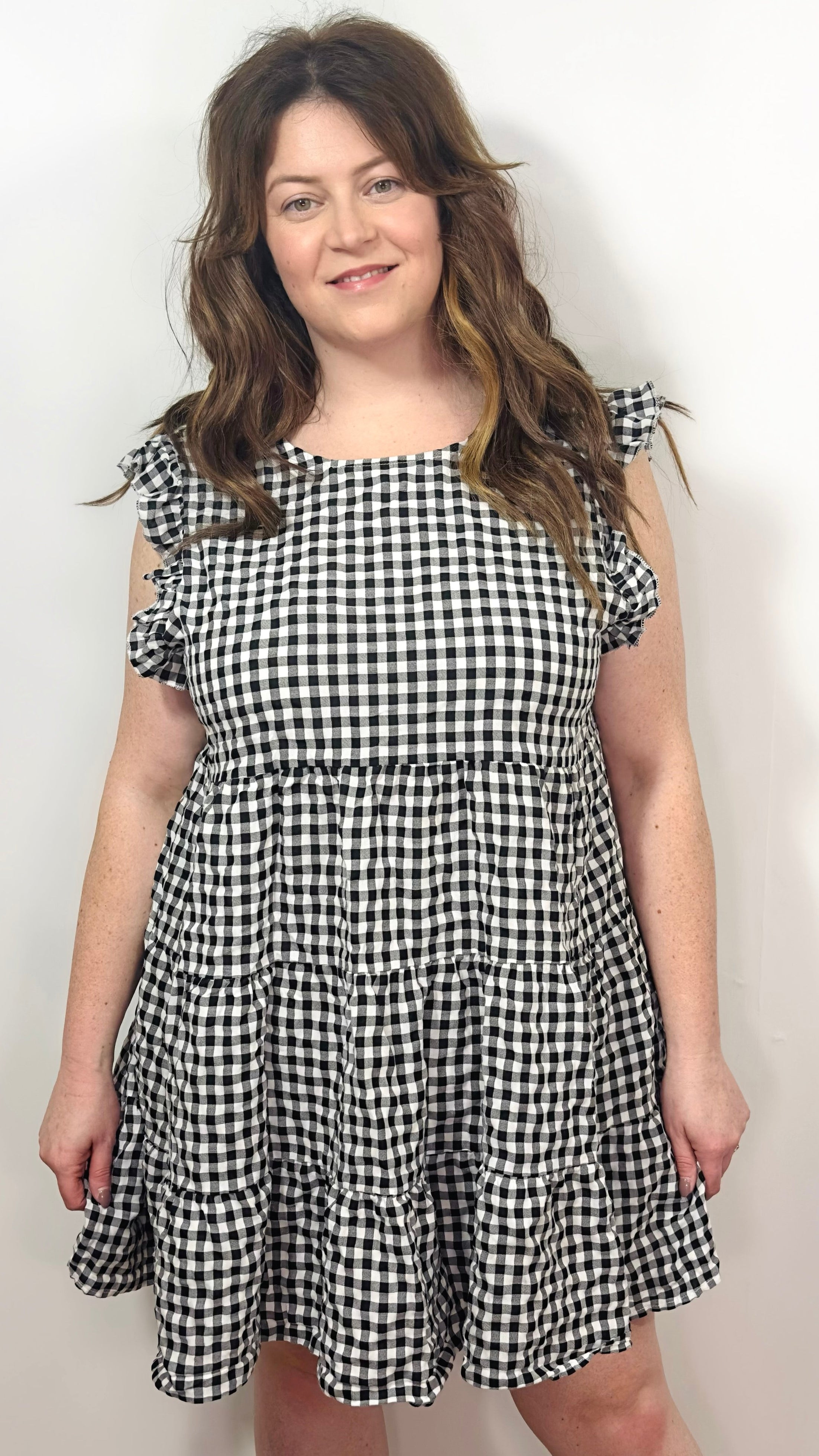 Woman wearing a black and white checkered dress against a plain background