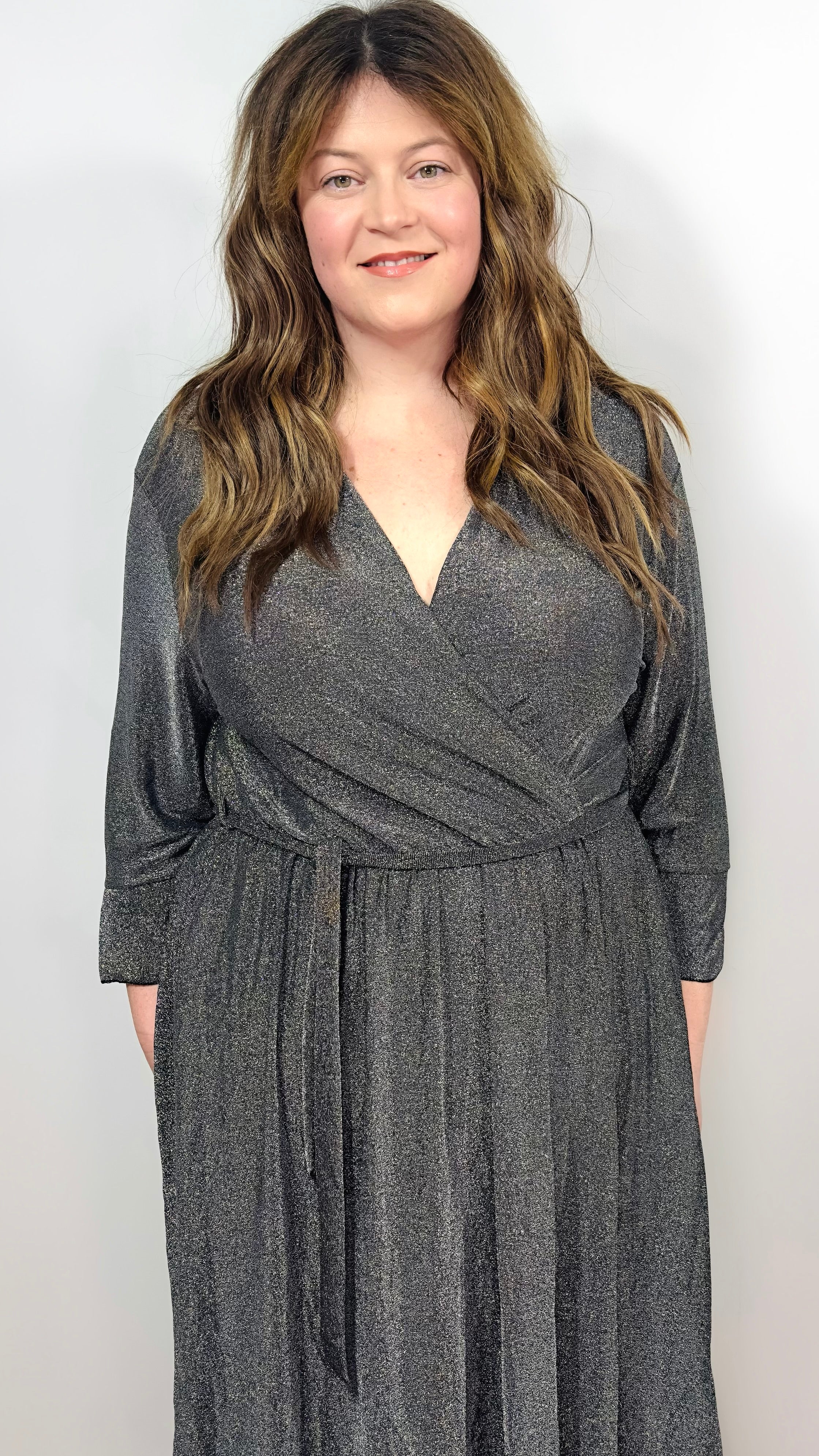 Woman wearing a silver wrap dress on a white background