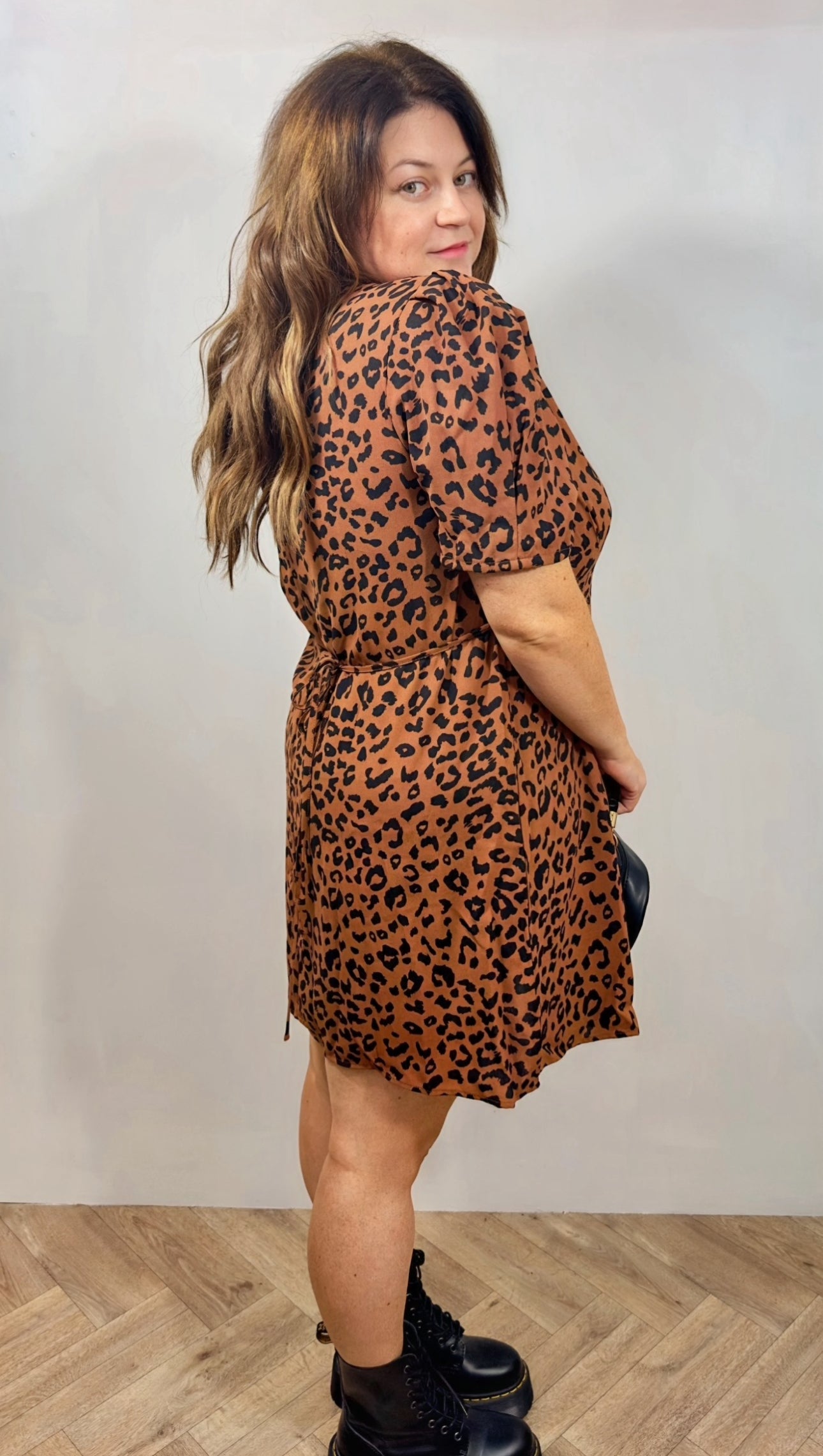 Woman wearing a leopard print dress against a plain background