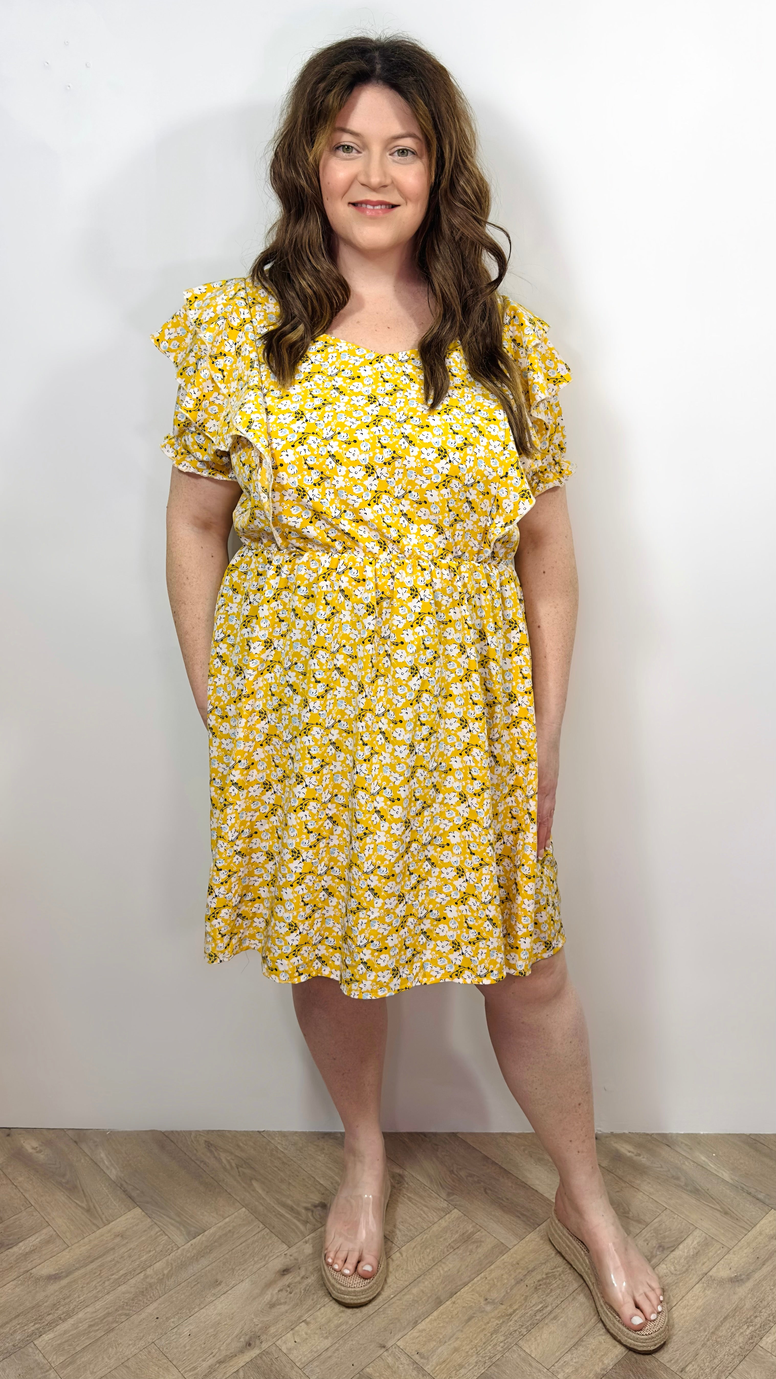 Woman wearing a yellow floral dress against a white background