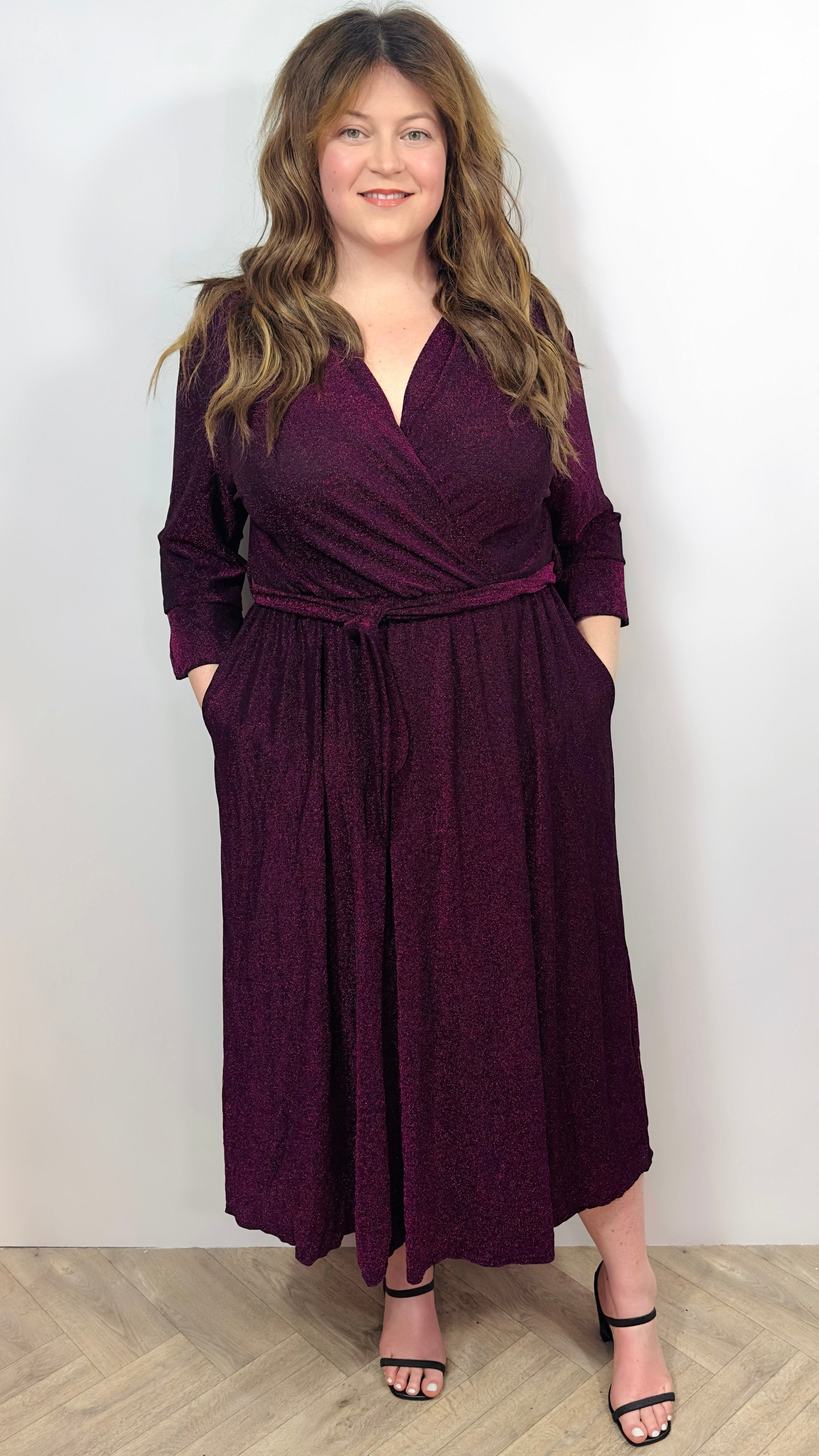 Woman wearing a burgundy wrap dress against a plain background