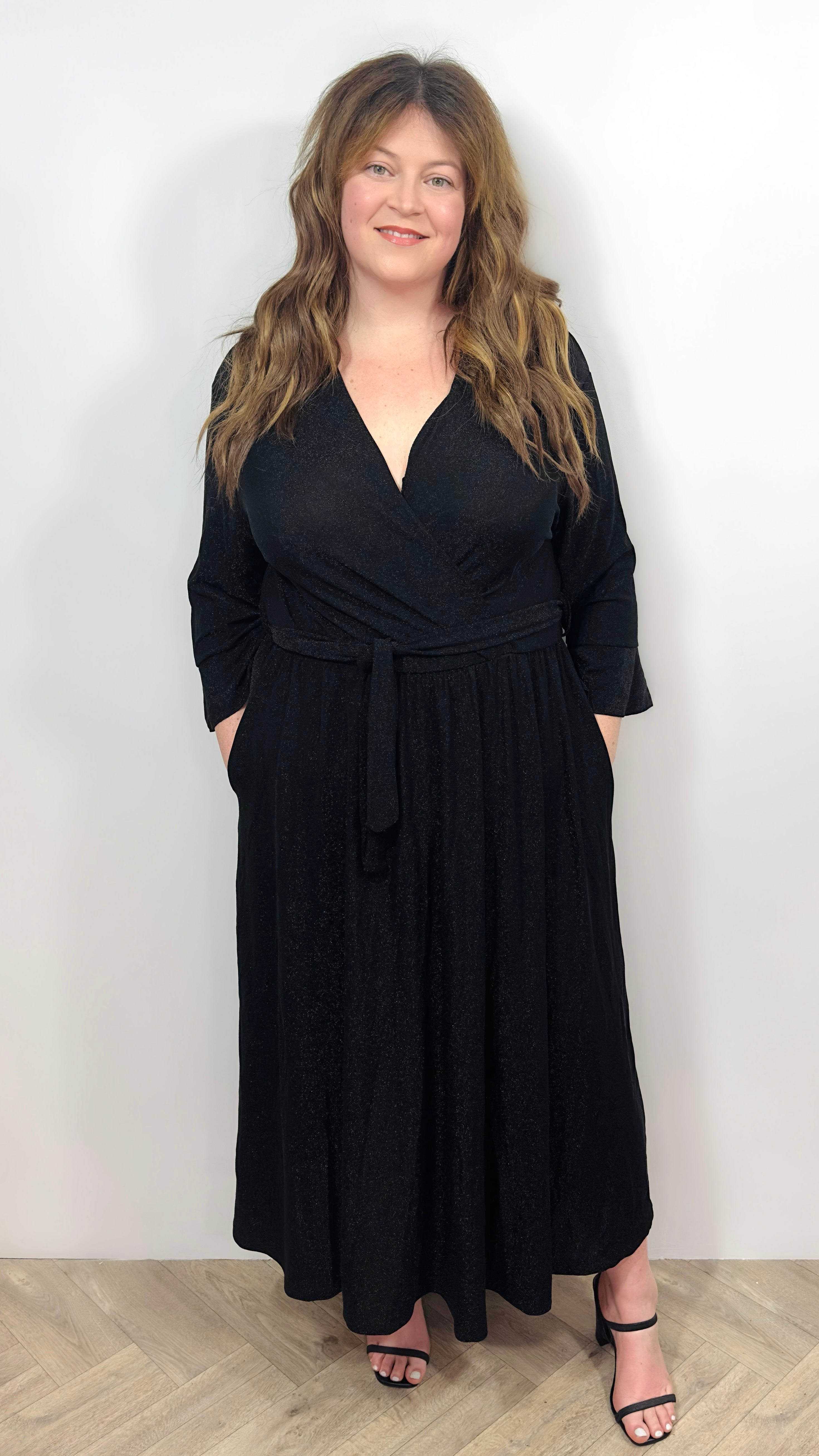 a woman wearing a black wrap dress with a white background
