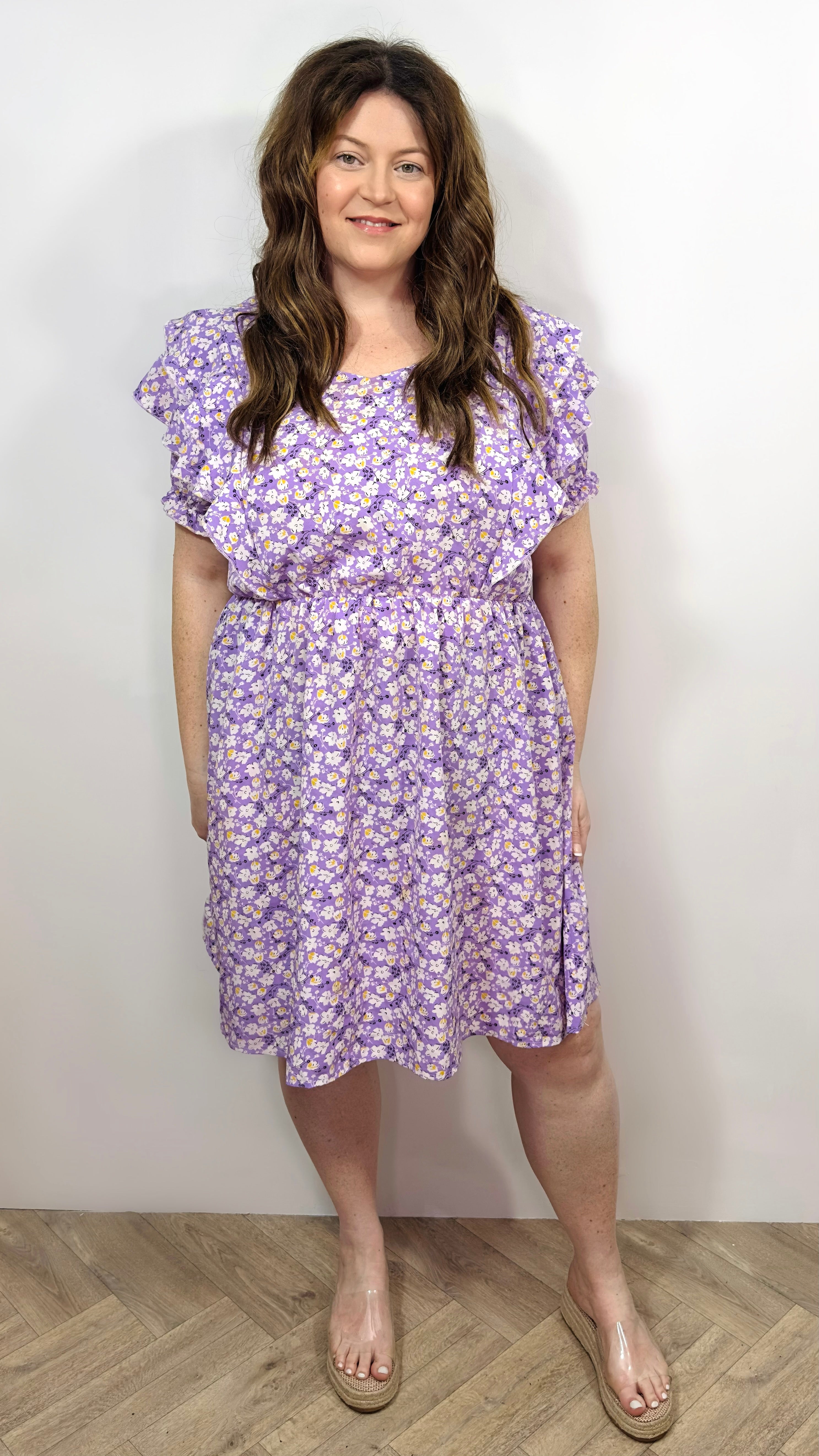 Woman wearing a purple floral dress against a white background