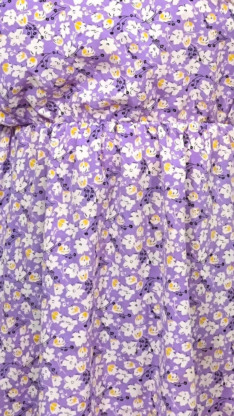 Woman wearing a purple floral dress against a white background