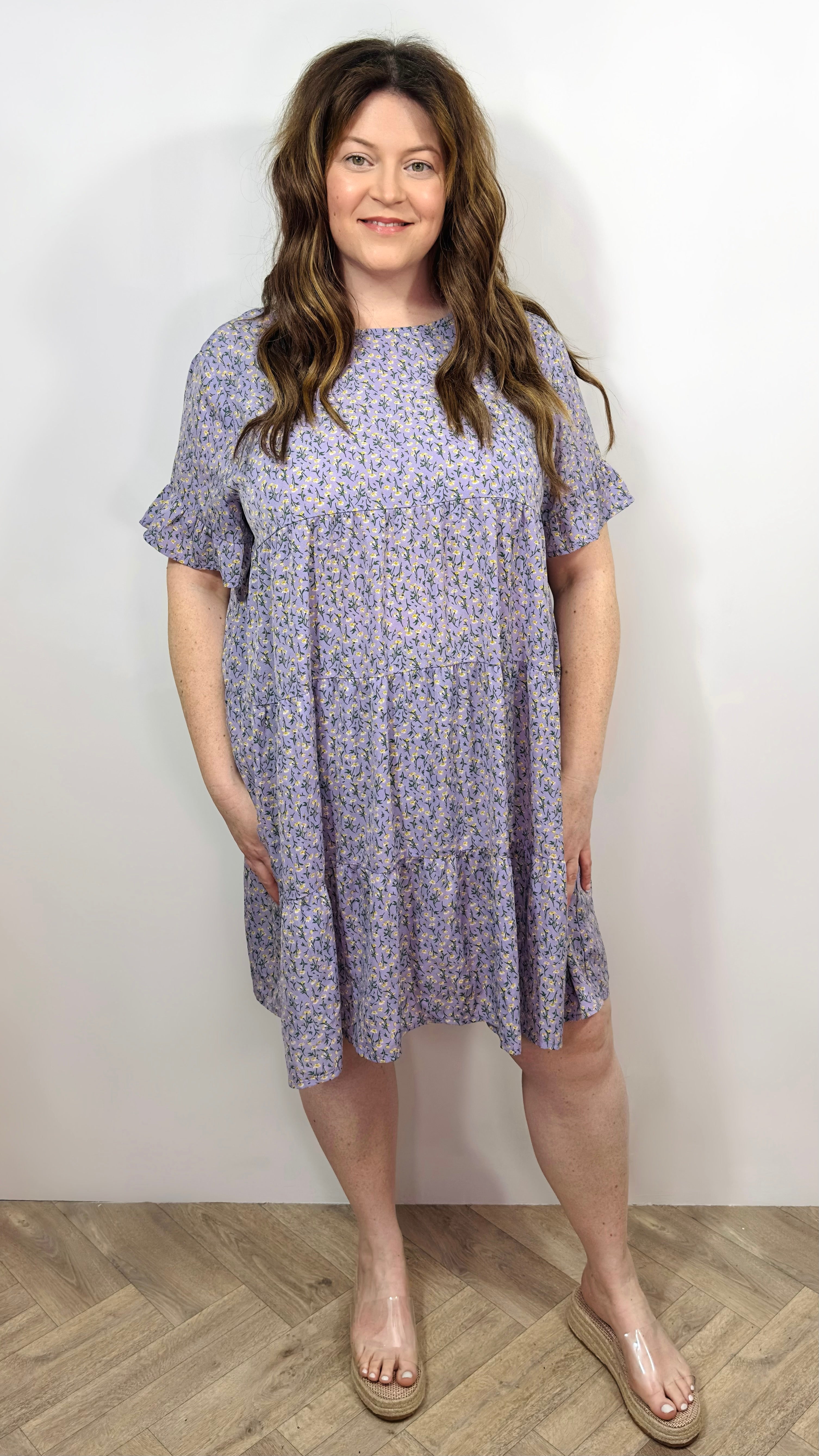 A woman wearing a floral smock dress with short sleeves and above knee length.