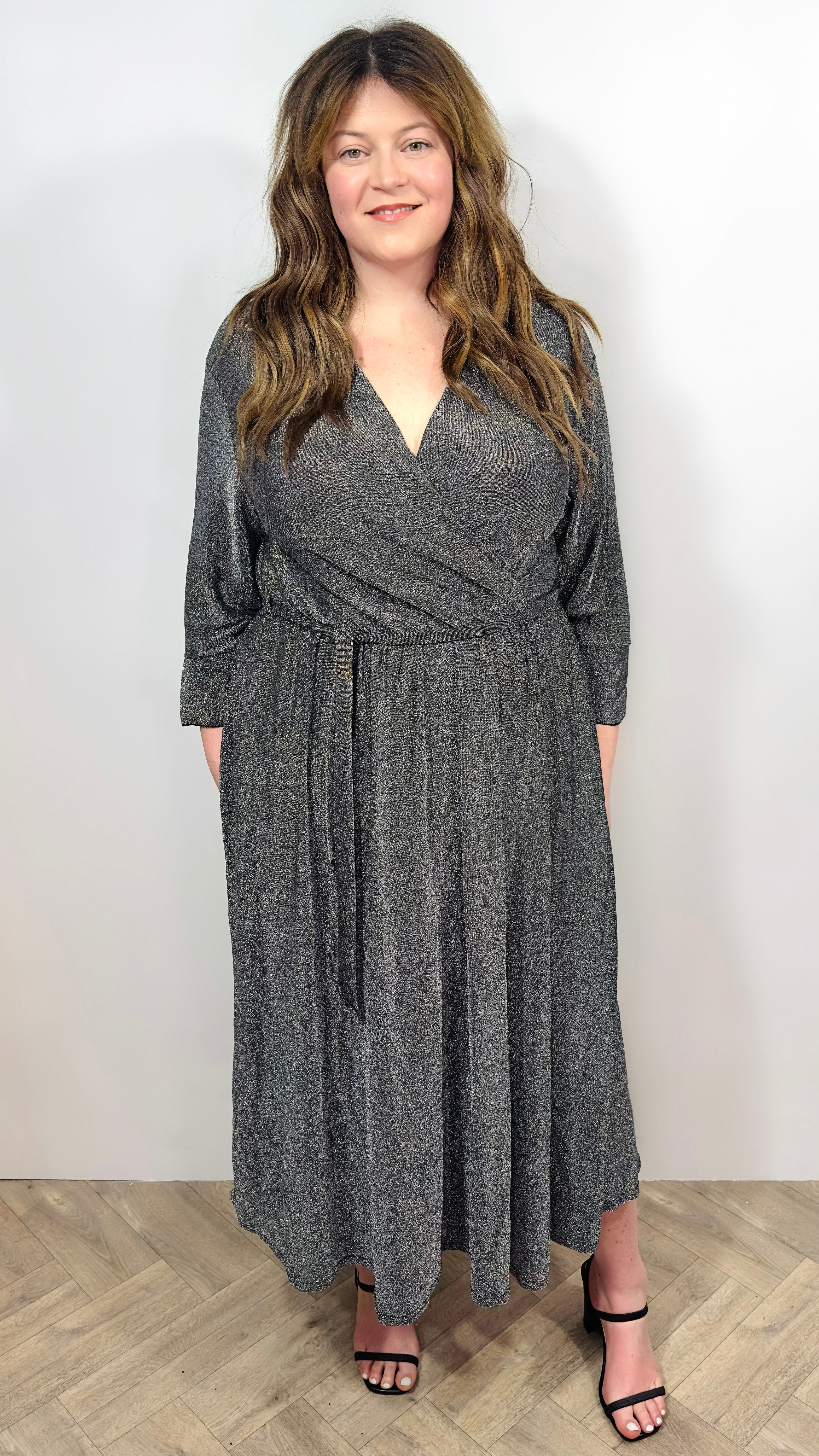 Woman wearing a silver wrap dress on a white background