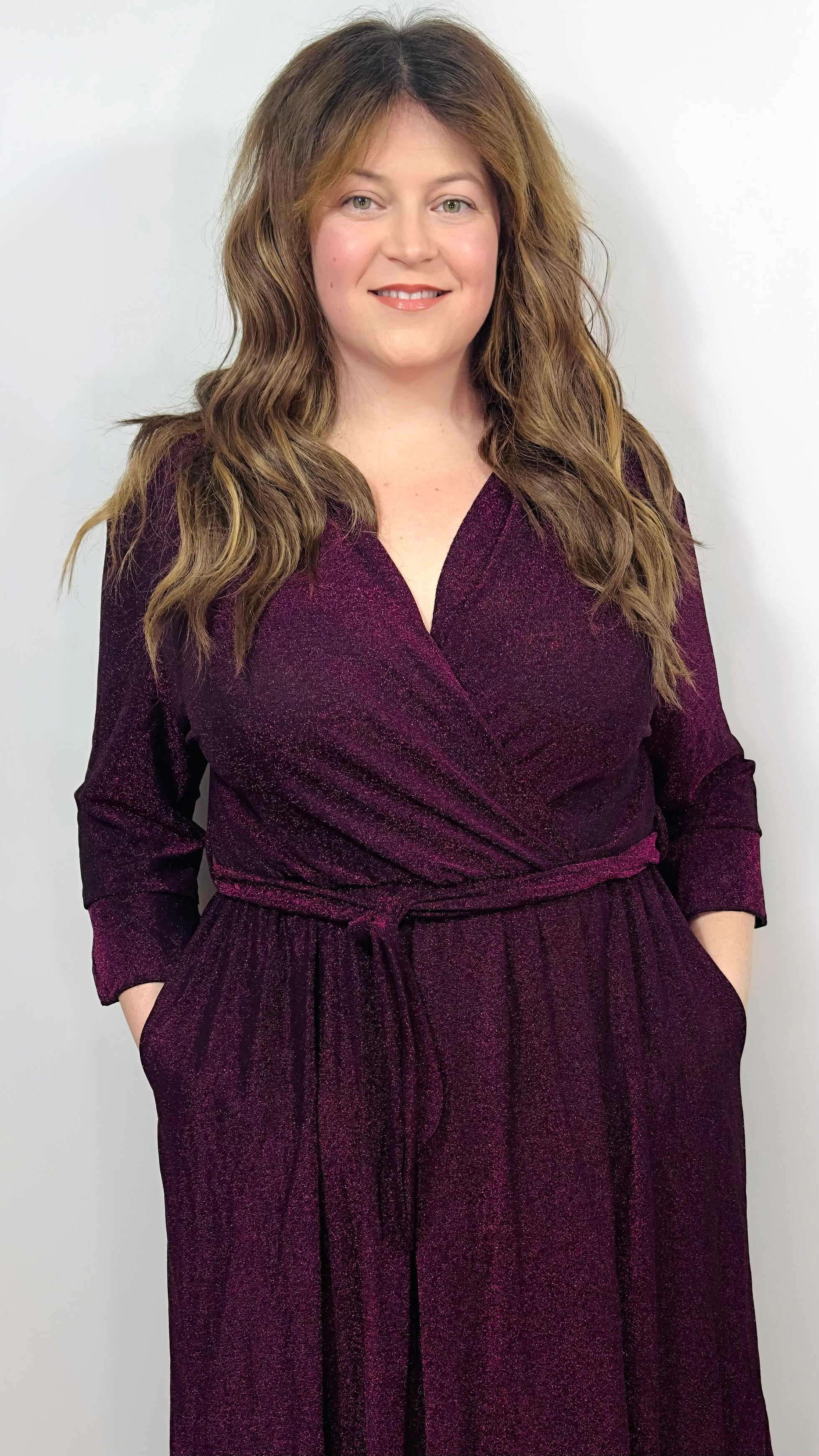 Woman wearing a burgundy wrap dress against a plain background