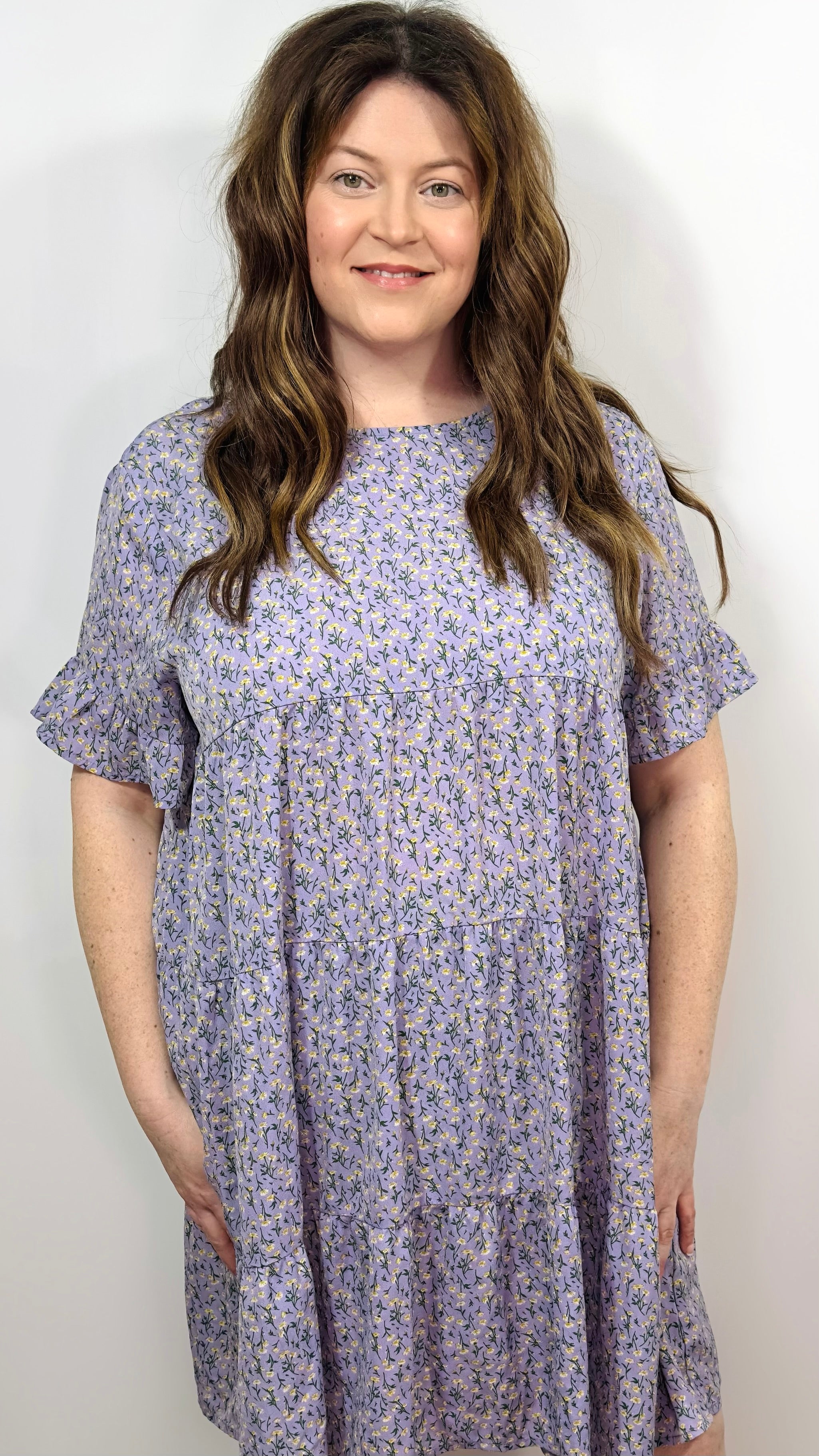A woman wearing a floral smock dress with short sleeves and above knee length.