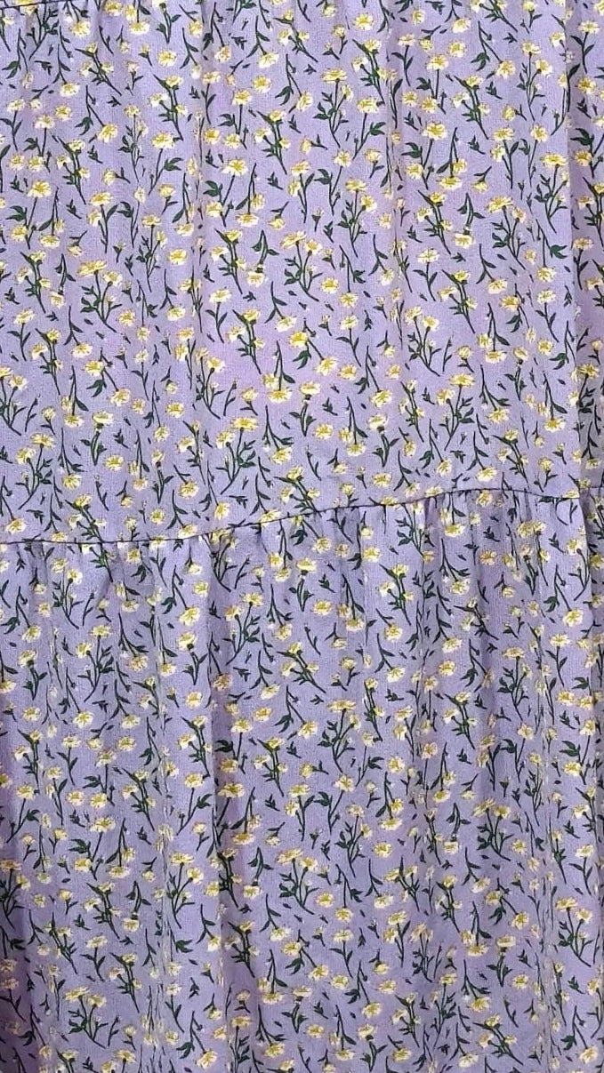 Floral patterned fabric with small yellow flowers and green leaves on a purple background