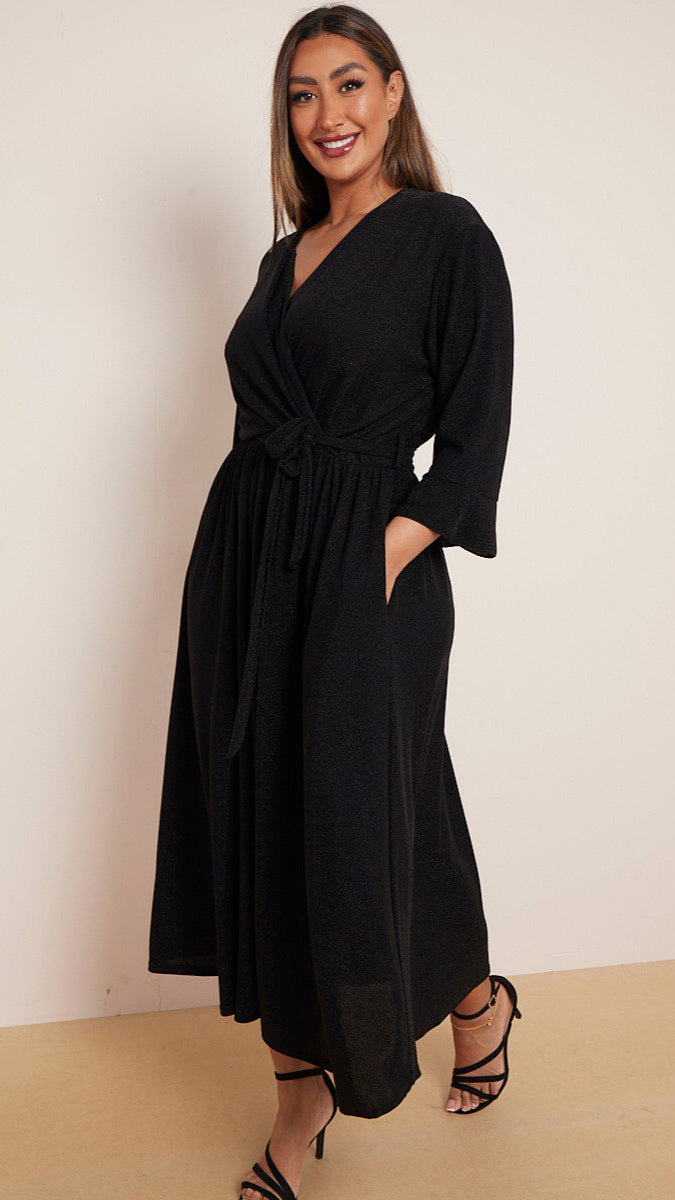 a woman wearing a black wrap dress with a white background