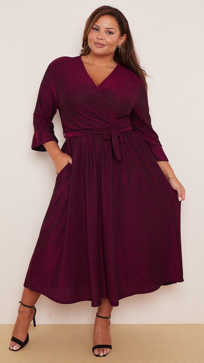 Woman wearing a burgundy wrap dress with a plain background