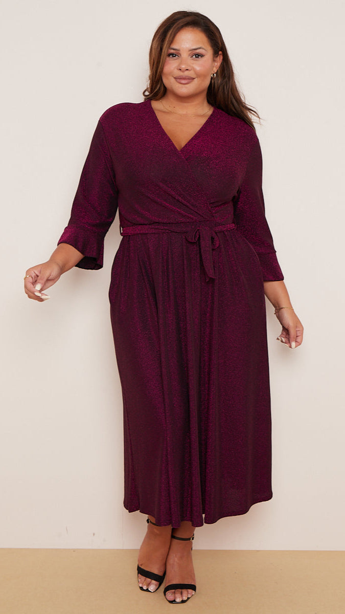 Woman wearing a burgundy wrap dress against a plain background